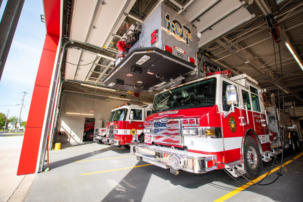 Two modern fire trucks parked in a clean fire station bay including a tower ladder