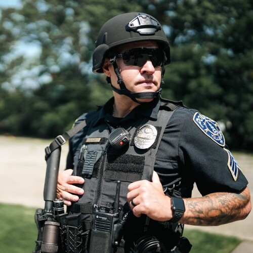 A close-up of tactical gloves on an operator wearing a plate carrier
