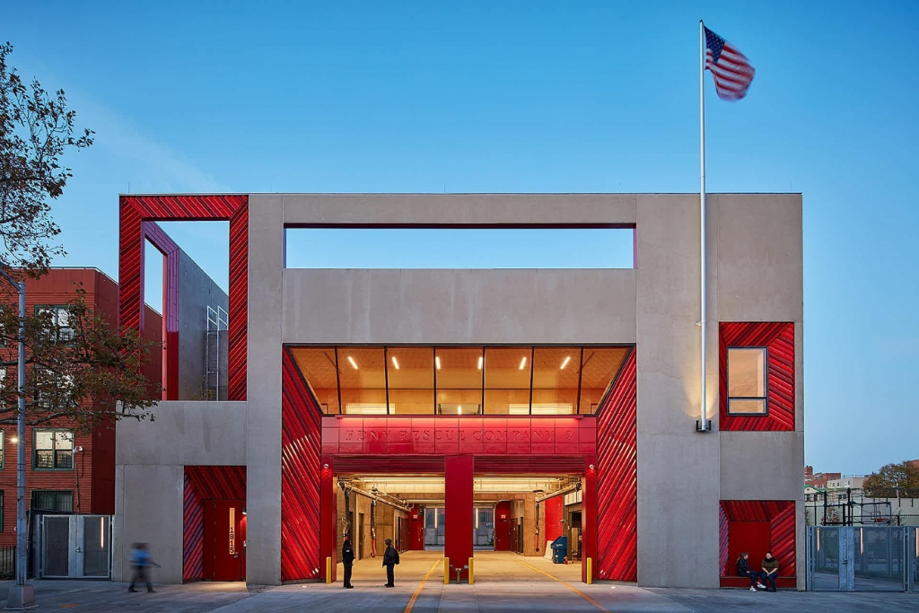 A modern fire station building with red and concrete architecture and an American flag