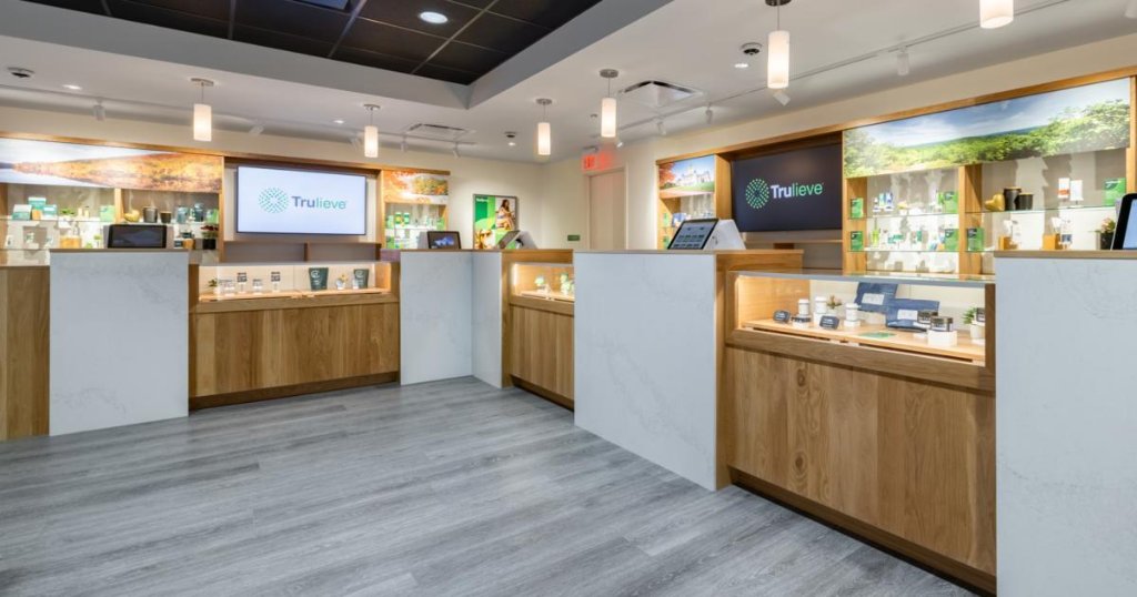 Inside a modern Trulieve dispensary, showing service counters, wood shelving and digital signage displaying the Trulieve logo.