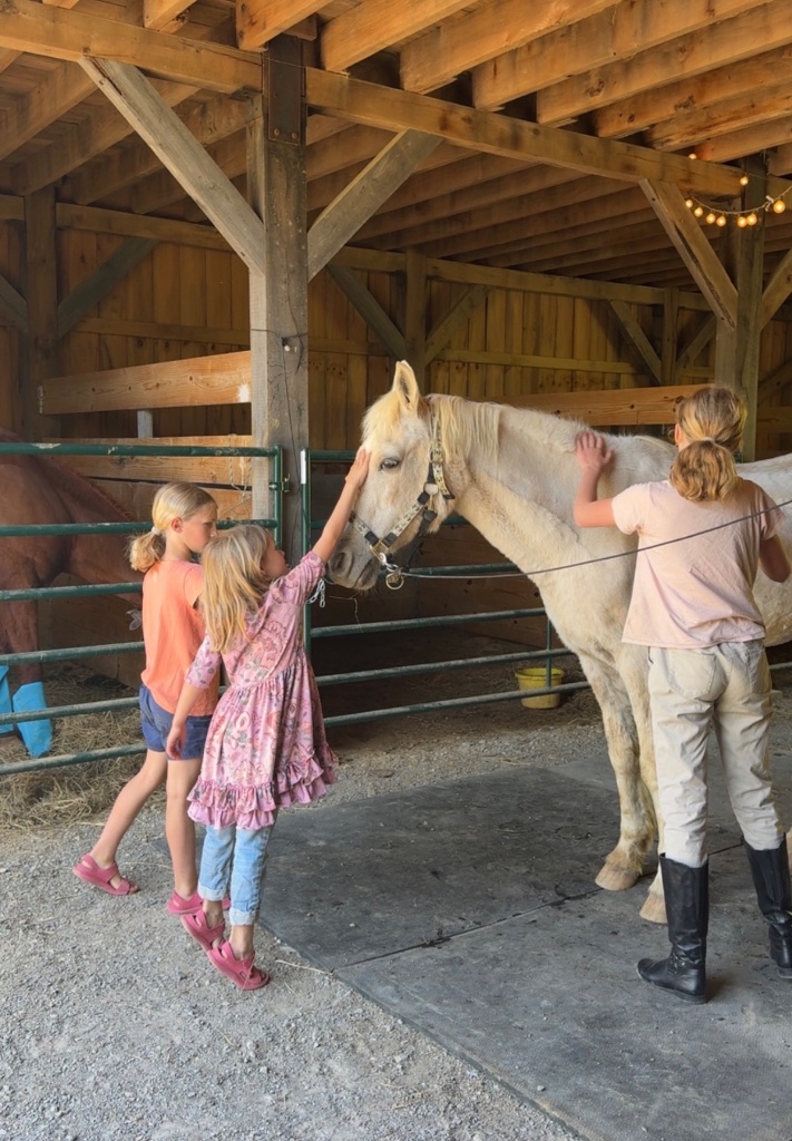 Girls interacting with horses inside the barn at Little Patch of Heaven