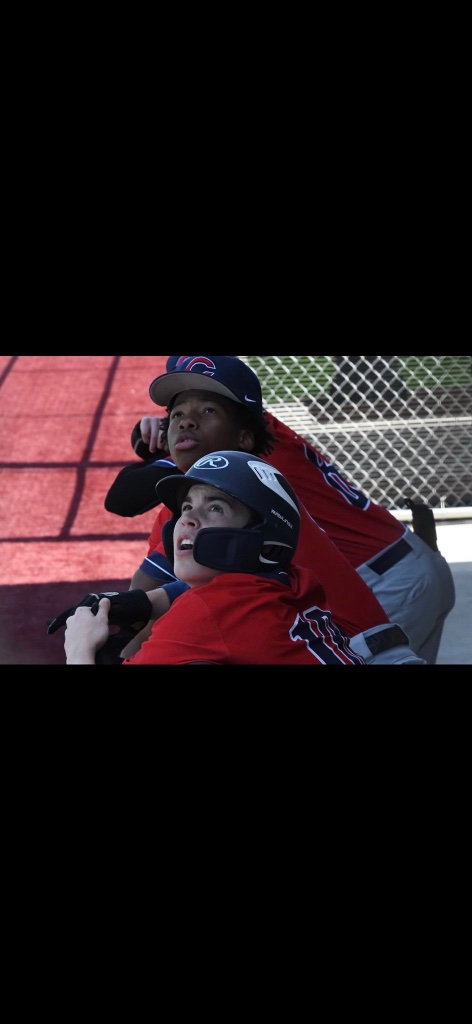Karmelo Anthony laughing with teammate in baseball dugout