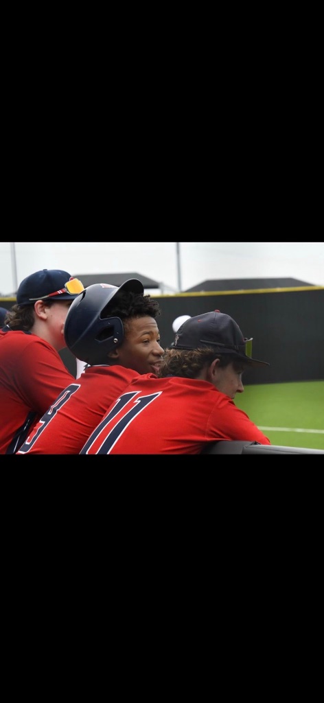 Karmelo Anthony with teammates in red baseball uniforms in the dugout