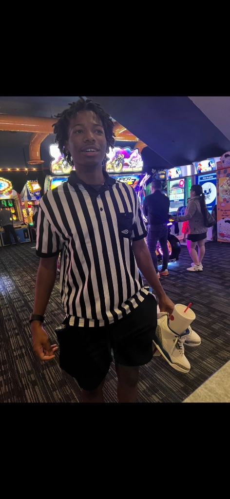 Karmelo Anthony smiling at arcade in striped shirt