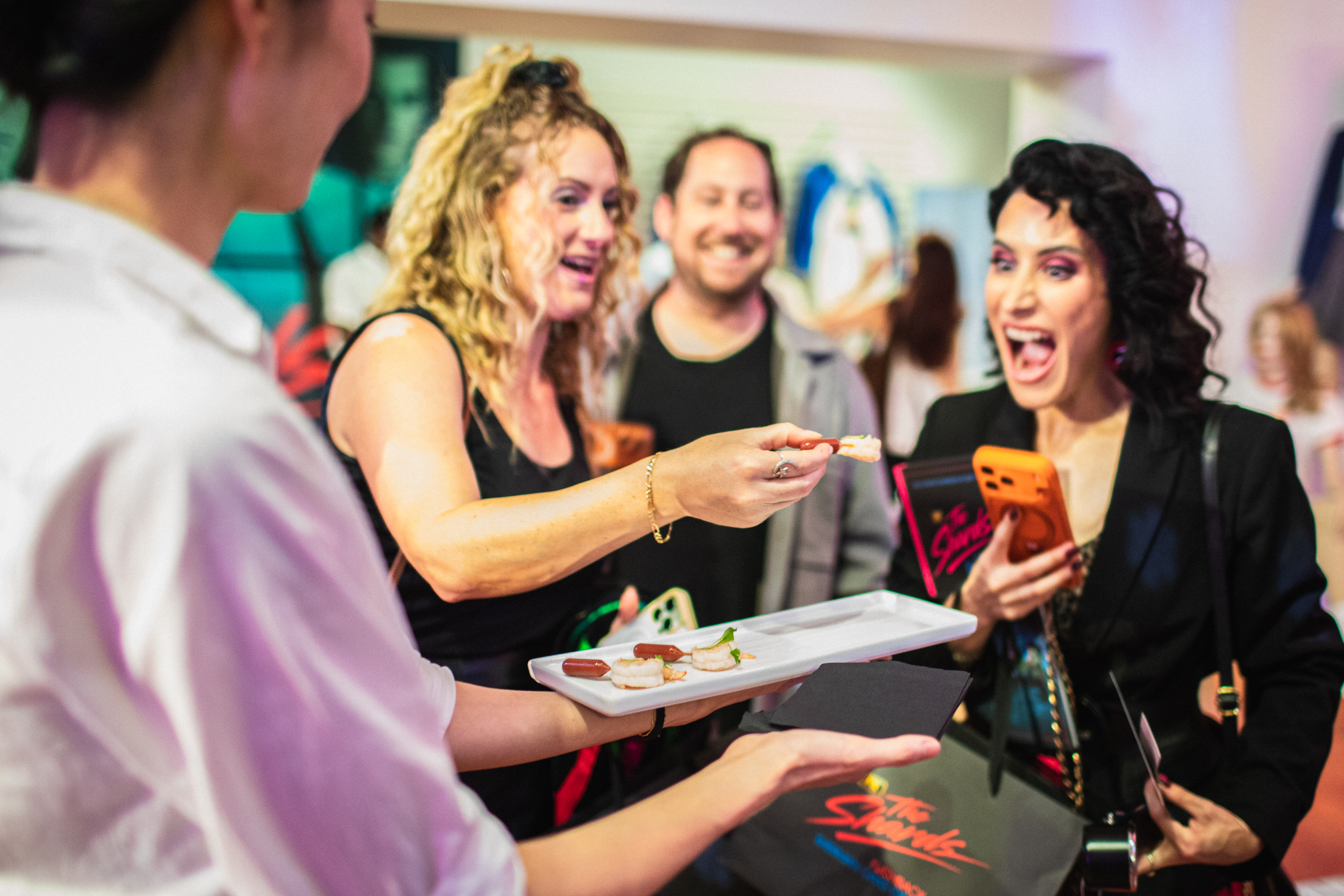 Server offering a tray of skewered shrimp appetizers to guests at The Shards event