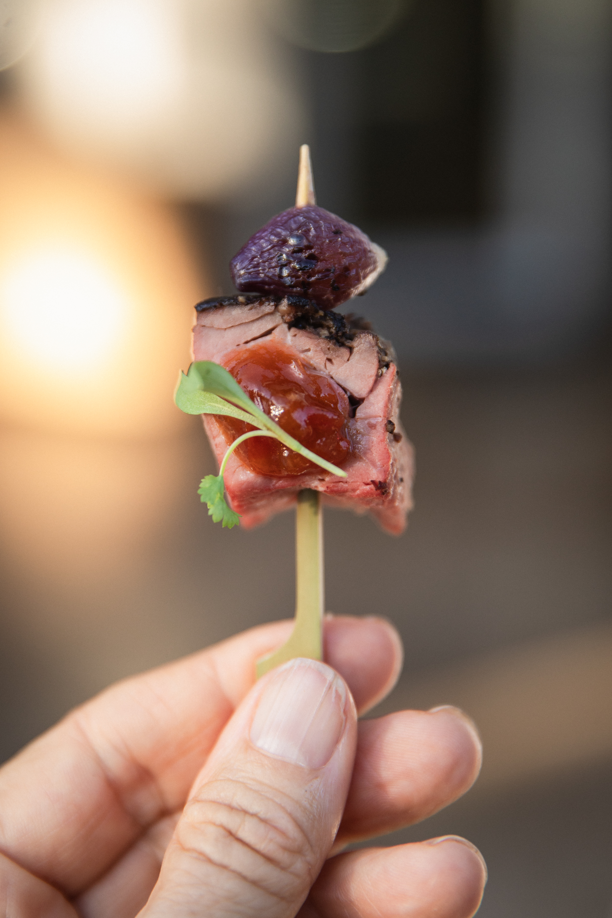 Seared beef cube with purple grape and fruit glaze on a bamboo skewer