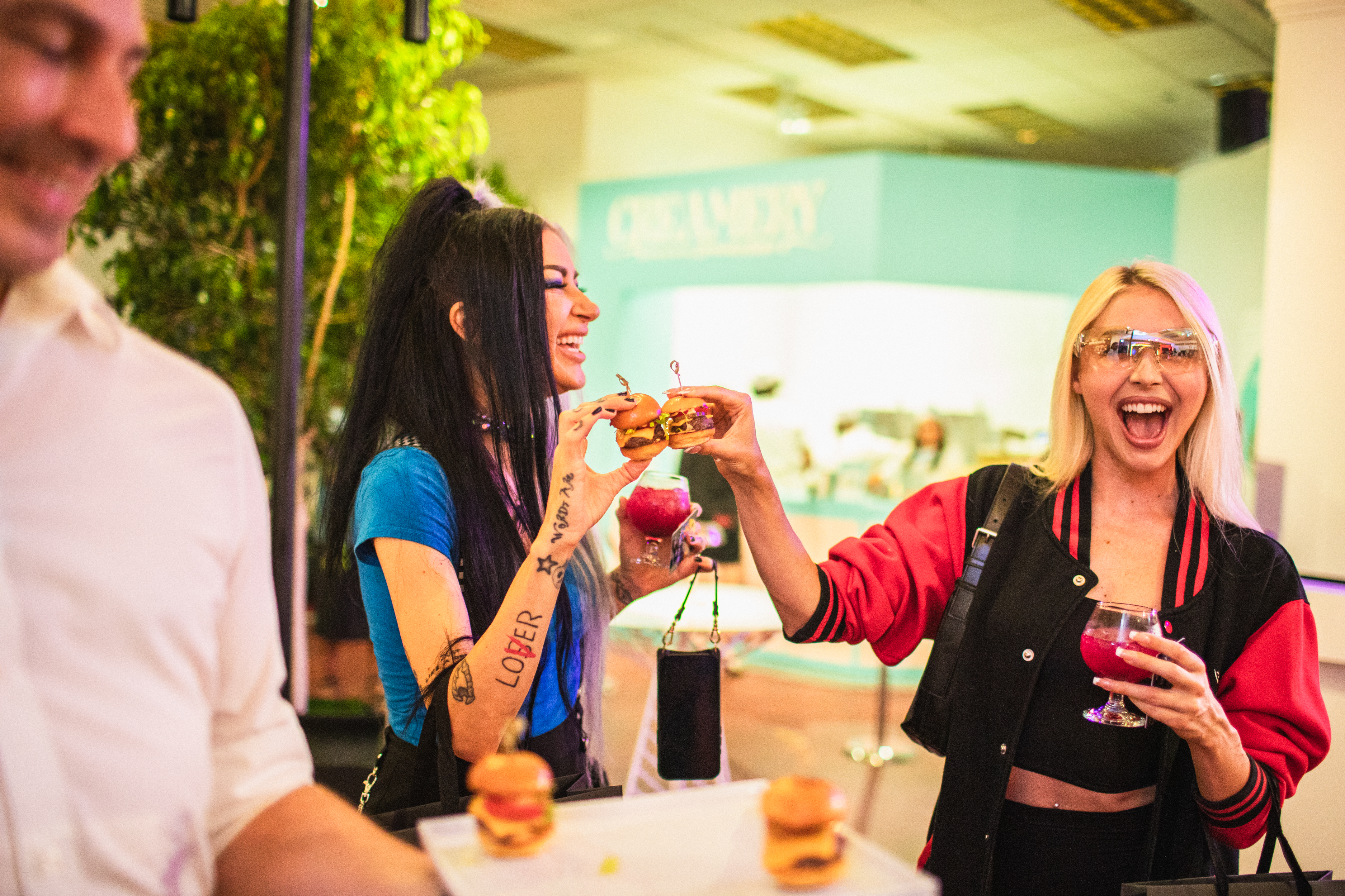 Guest passing a slider to a delighted friend at a lively catered event