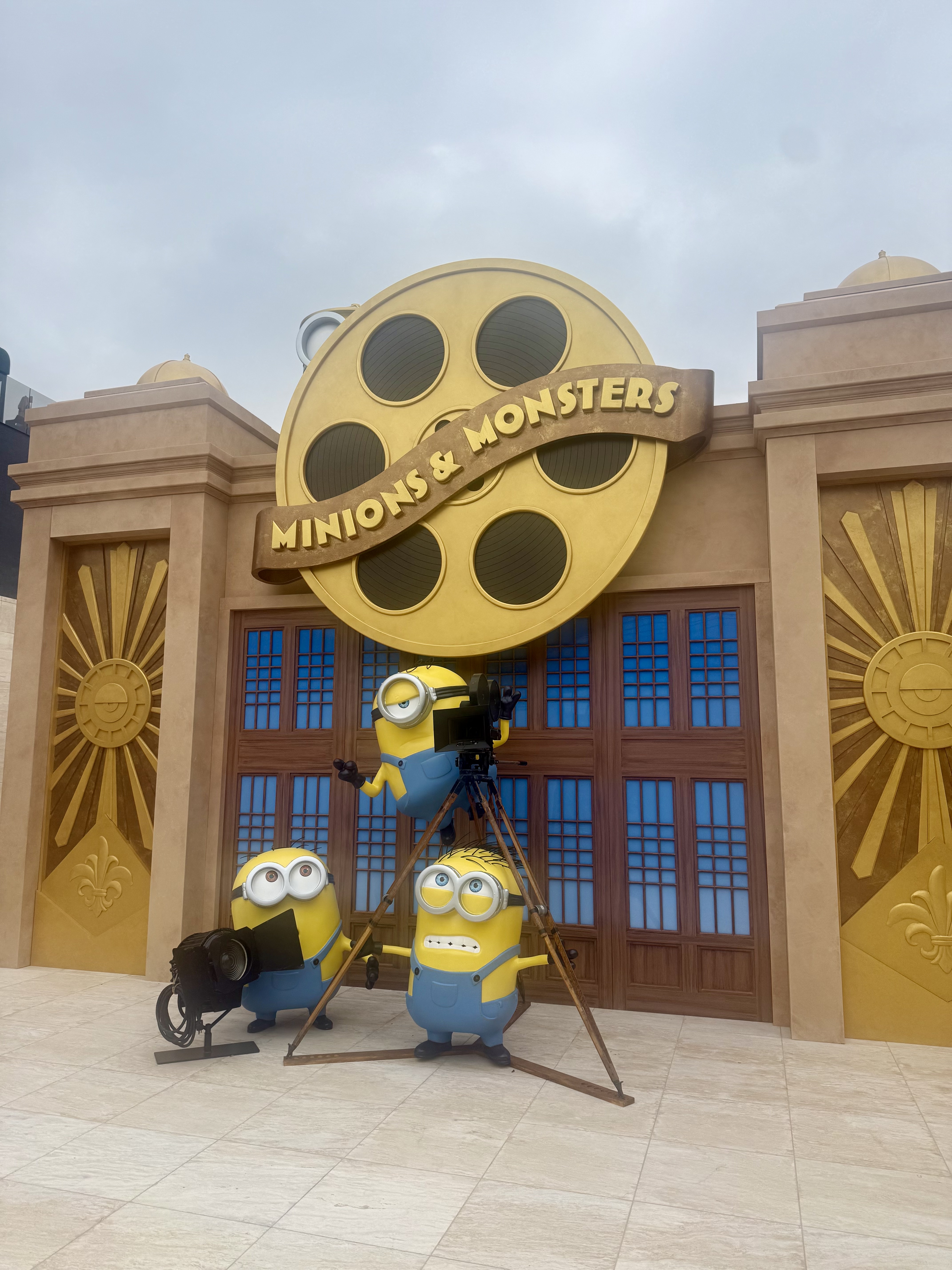 Theatrical Minions & Monsters movie premiere entrance set with a gold film reel prop and Minion figures at Milk Studios