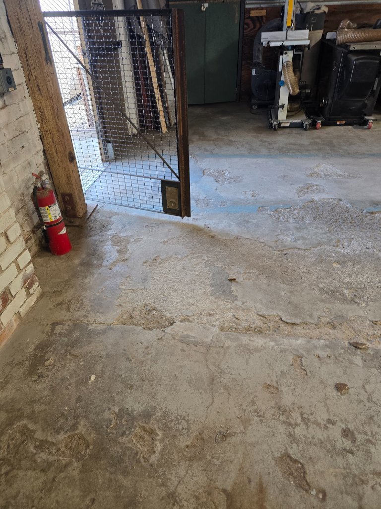 Damaged spalled concrete workshop floor before epoxy resurfacing by Epoxy Renovations
