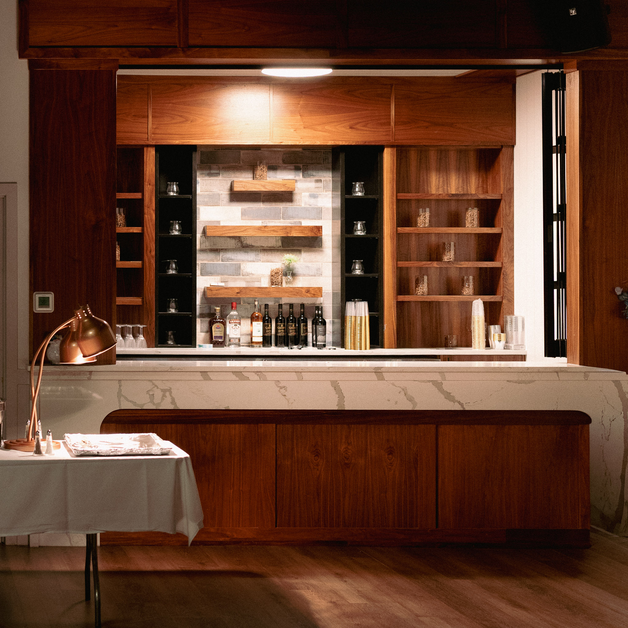 Built-in wooden bar area with marble countertop and shelving