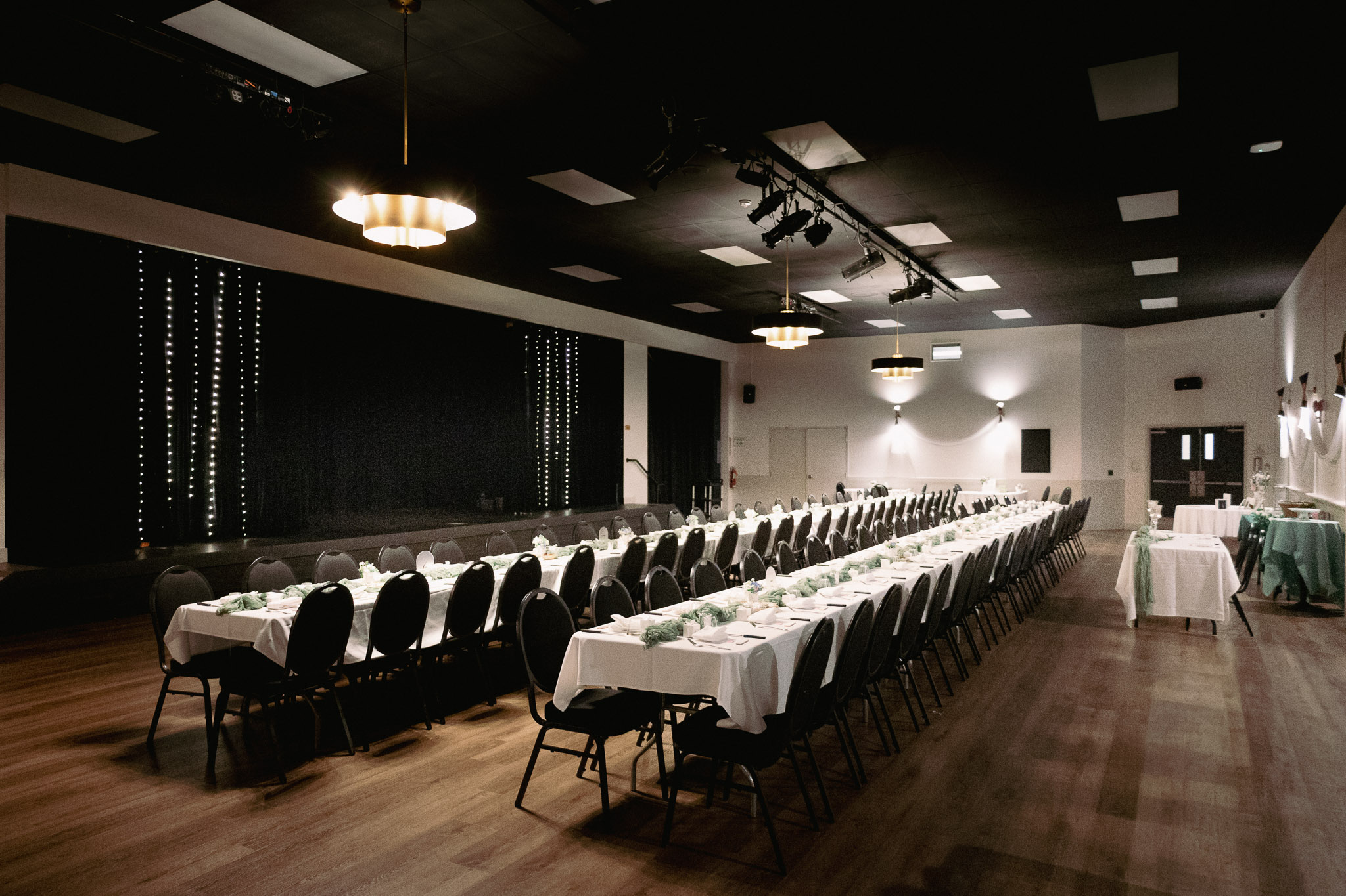 Bearspaw banquet hall set up for a wedding reception with stage and fairy lights