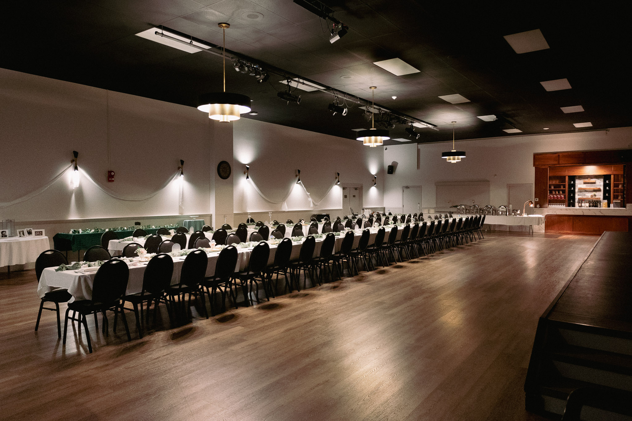 Wide view of the banquet hall with long dining table and bar