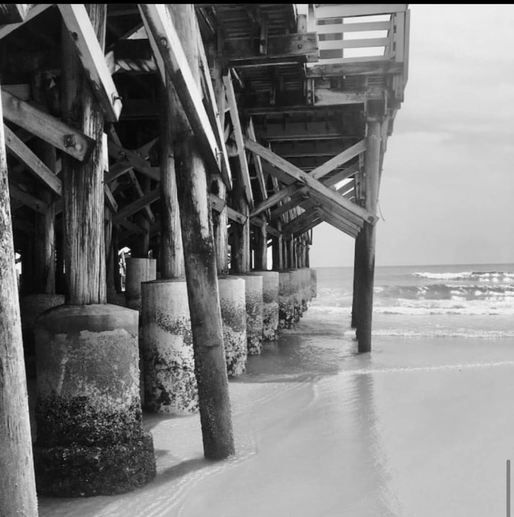 The underside of a wooden pier stretching over the ocean