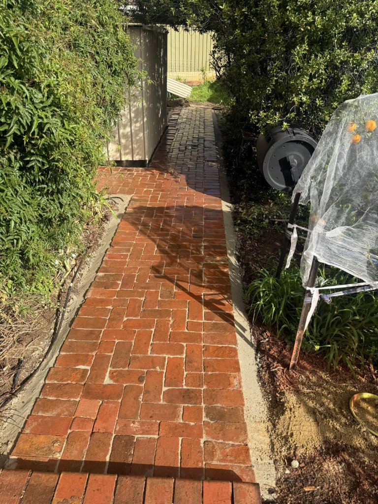 Old red brick path laid in a 90-degree herringbone pattern