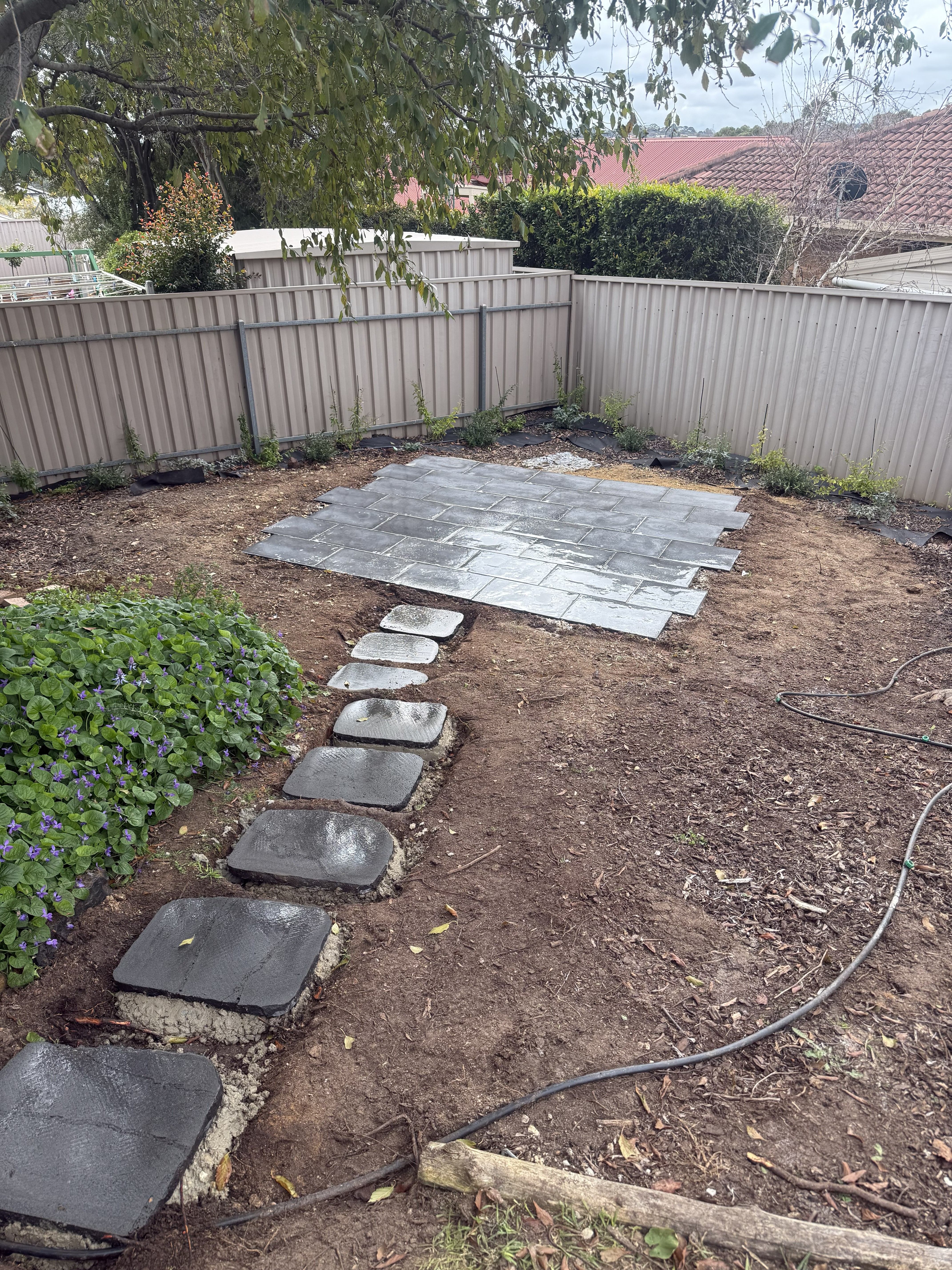 Stepping stone path leading down to a small paved patio area