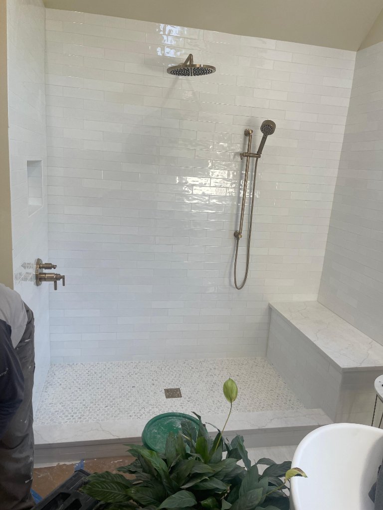 White subway tile shower with pebble floor and bench