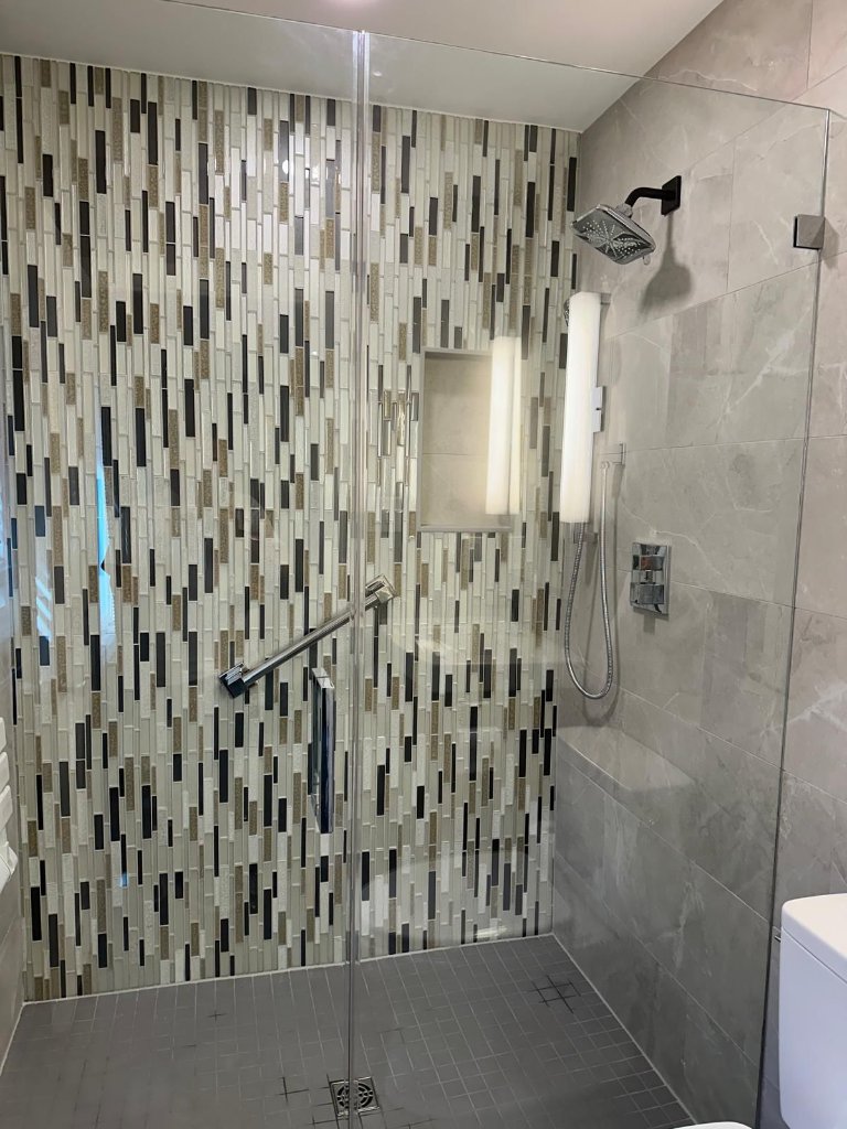Modern glass shower with mosaic tile accent wall