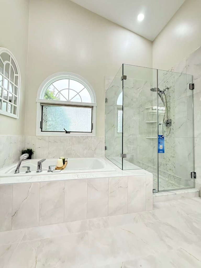 Bright white marble bathroom with soaking tub and glass shower