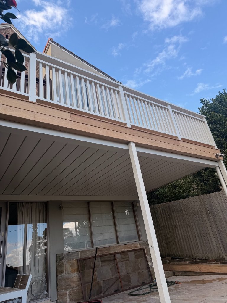 Mid-build raised Blackbutt deck with white aluminium balustrade going up