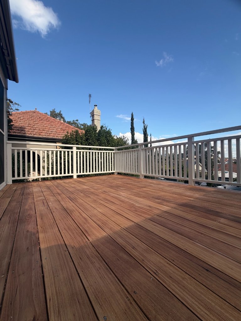 White aluminium balustrade wrapping raised Blackbutt deck with covered pergola below