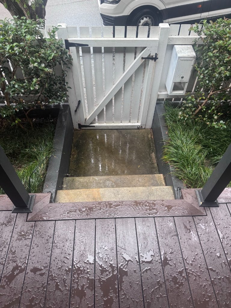 WPC composite deck gate detail with black steel posts and white timber gate