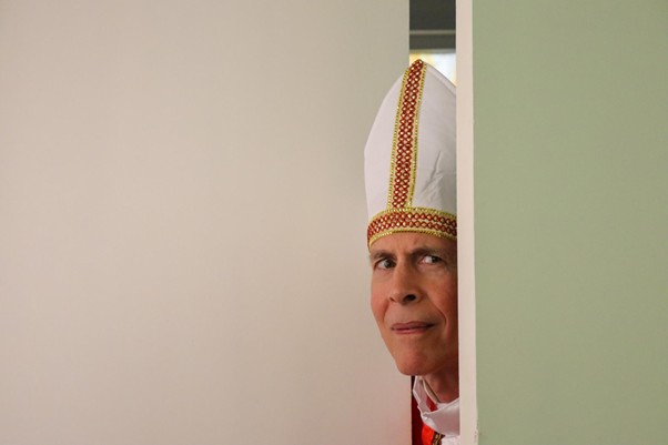 Behind the scenes - bishop in mitre peering from behind doorway