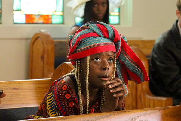 Woman in church pew with colorful headwrap