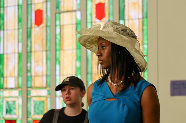 Woman in church hat by stained glass