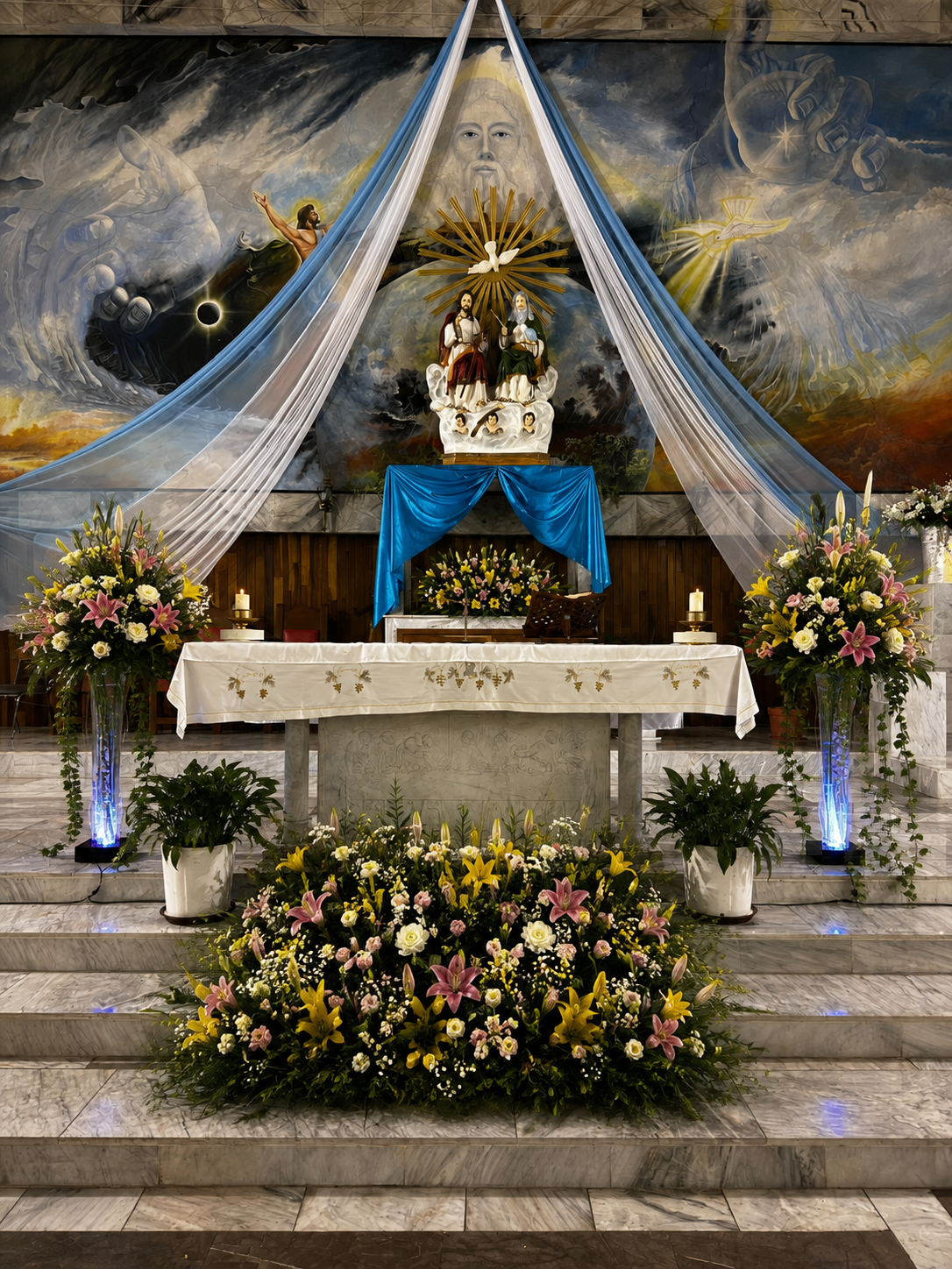 Altar con arreglo floral y escultura de la Trinidad