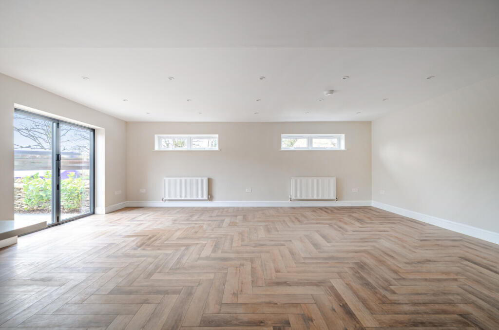 Empty unfurnished living room before virtual staging — open-plan layout with bare floors and neutral walls