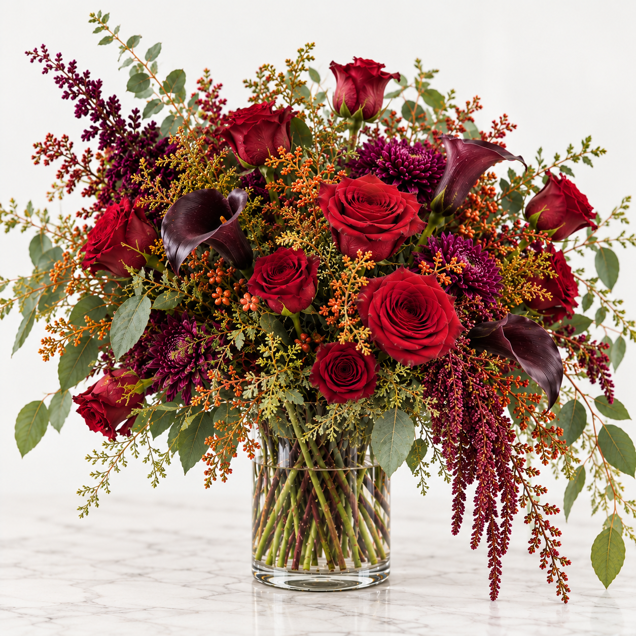 Wicked Wine Halloween arrangement of deep red roses, burgundy chrysanthemums and black calla lilies in a clear glass cylinder vase.