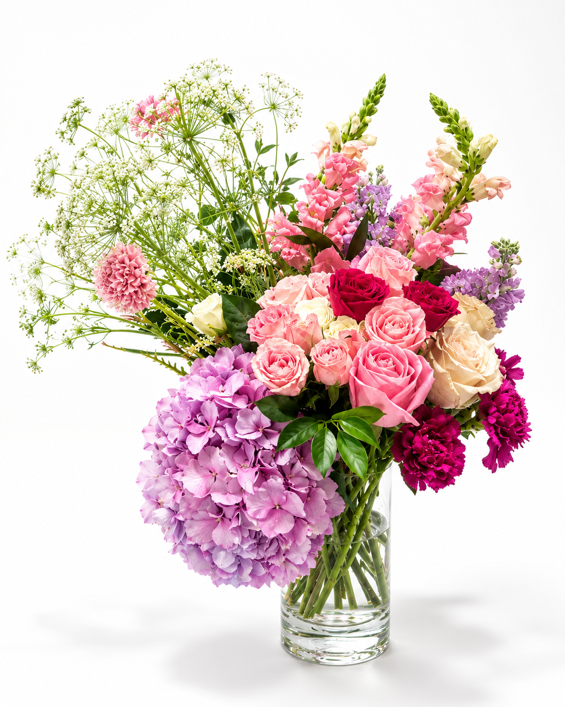 standard: Romantic lavender hydrangea, pink and magenta garden roses, Queen Anne's lace, and pink snapdragons in a clear cylindrical glass vase — custom love and romance flower delivery in Las Vegas NV.