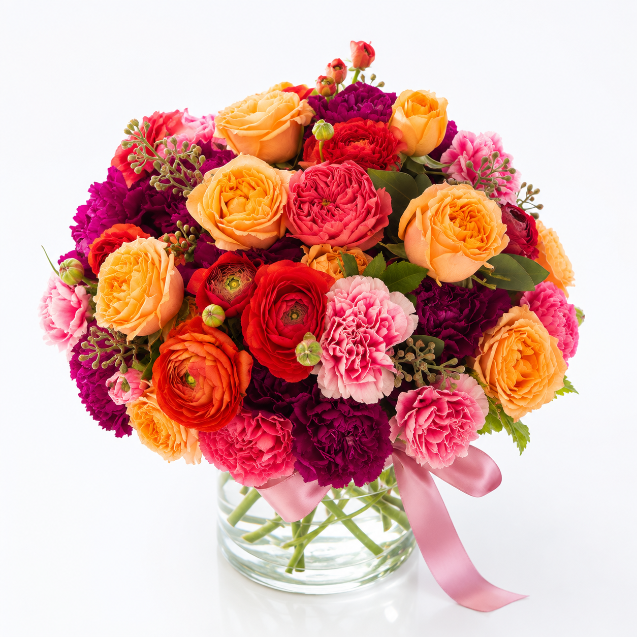 standard: Lush magenta, burnt orange, and red garden roses with ranunculus and carnations in a clear glass vase tied with a soft pink ribbon — congratulations flower arrangement for same-day delivery in Las Vegas.