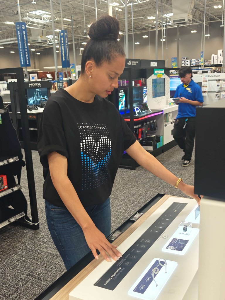Woman interacting with Tangem ring display kiosk at Best Buy