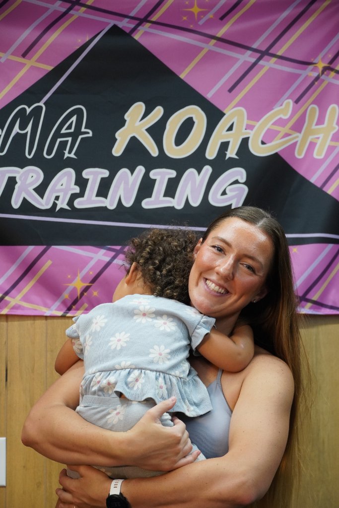 Danielle, founder of Mama Koach Training, holding her daughter