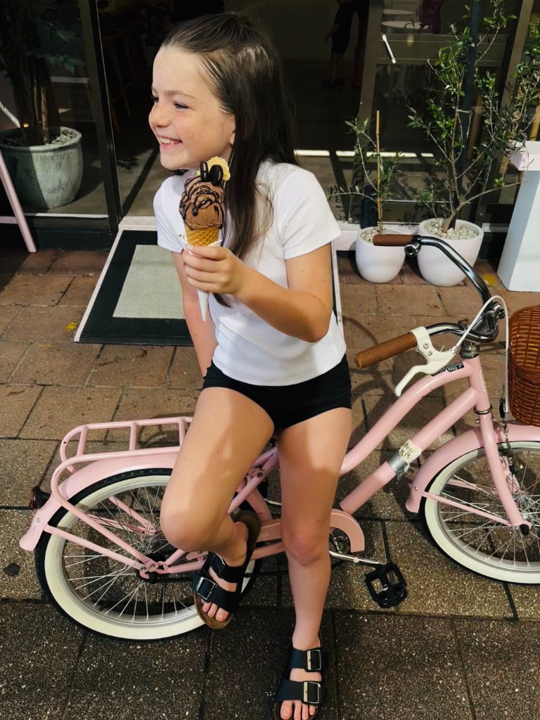 Girl on pink bike with ice cream cone