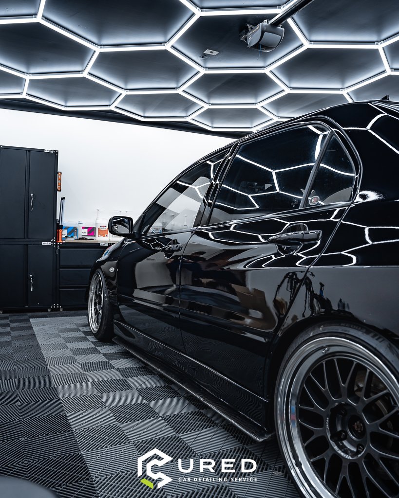 Black lowered car in Cairnlea detailing studio under hexagon lights - Cured Car Detailing