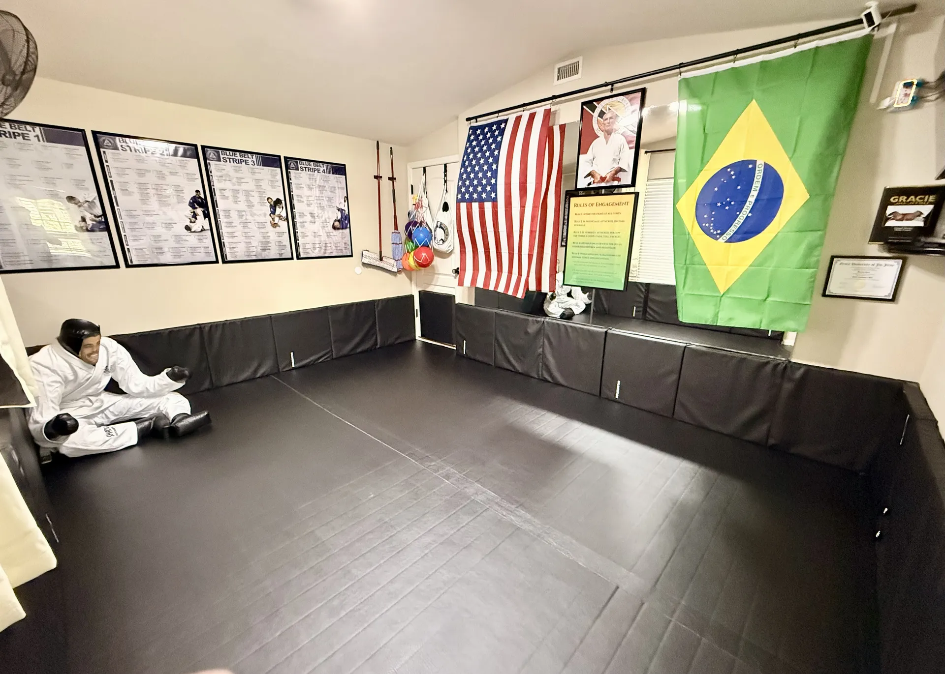 The Garage Gators BJJ training space in Gainesville FL with black puzzle mats, padded walls, and Gracie University posters