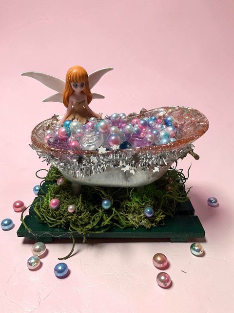 GlimmerBath Fairy Edition - fairy soaking in a pearl-filled enchanted tub on pink background