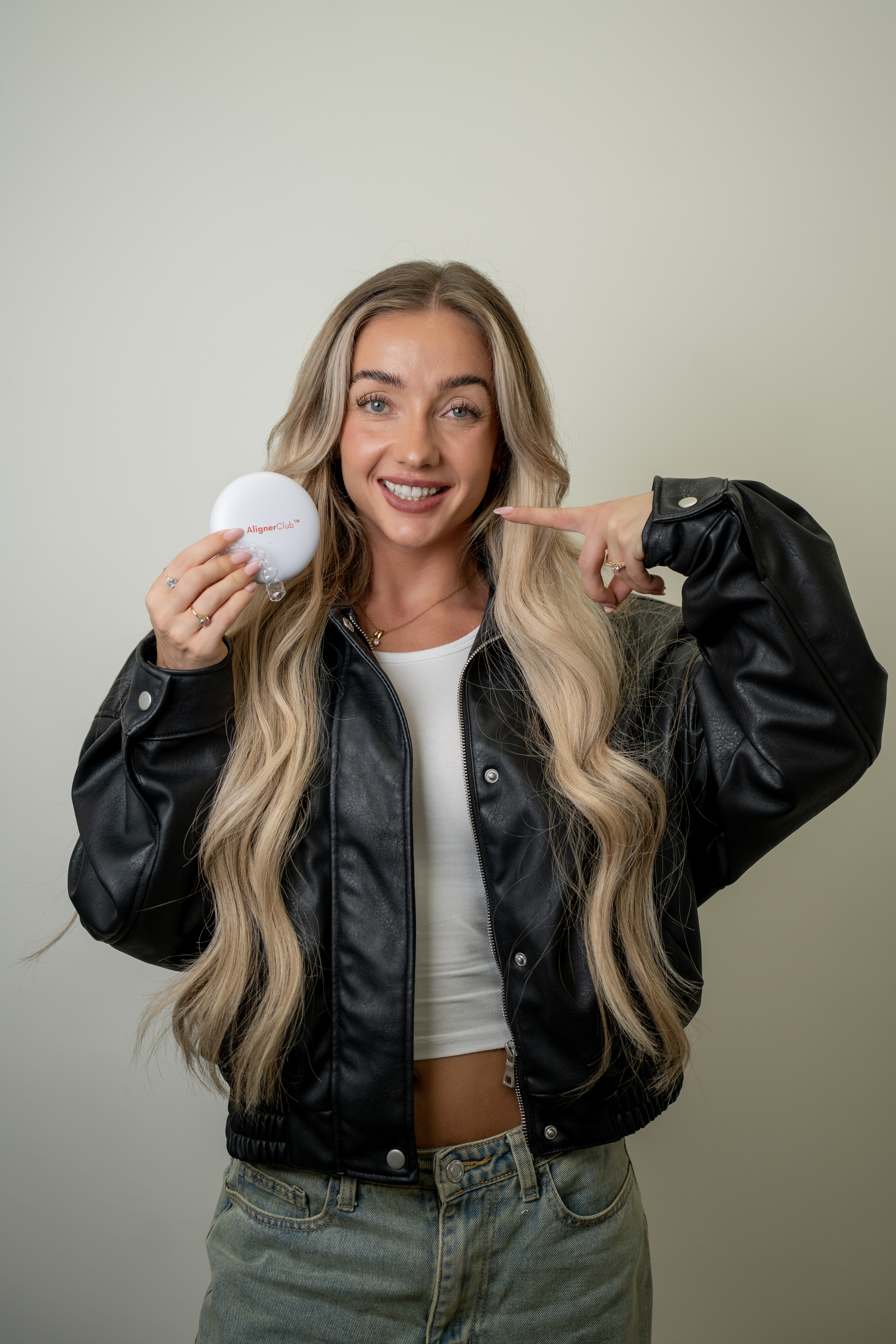Smiling Aligner Club patient pointing to her aligner case