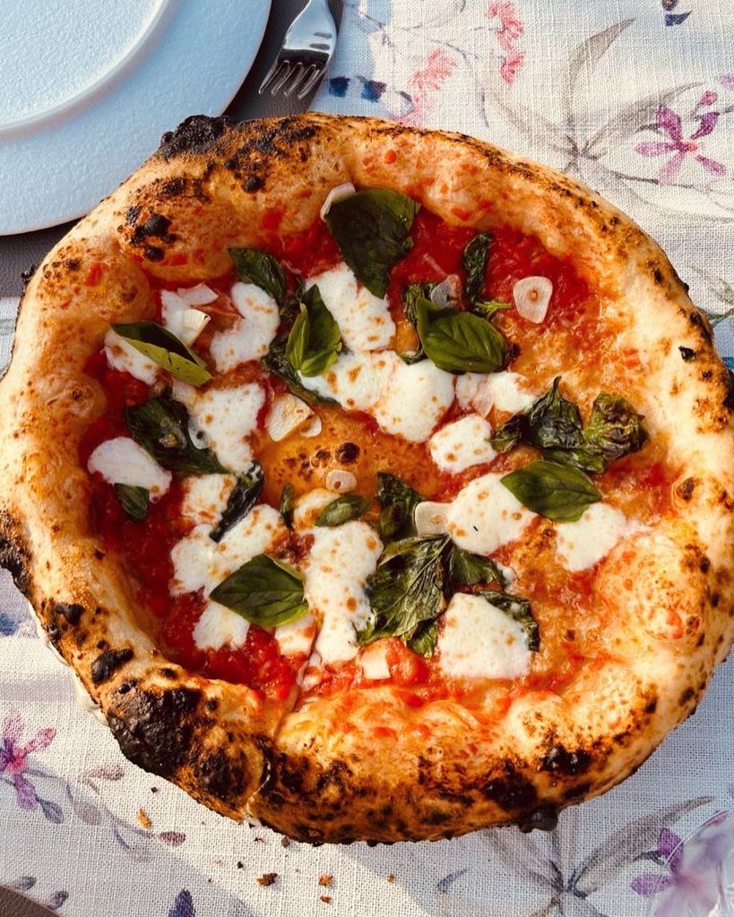 Drizzling olive oil from copper jug over pizza