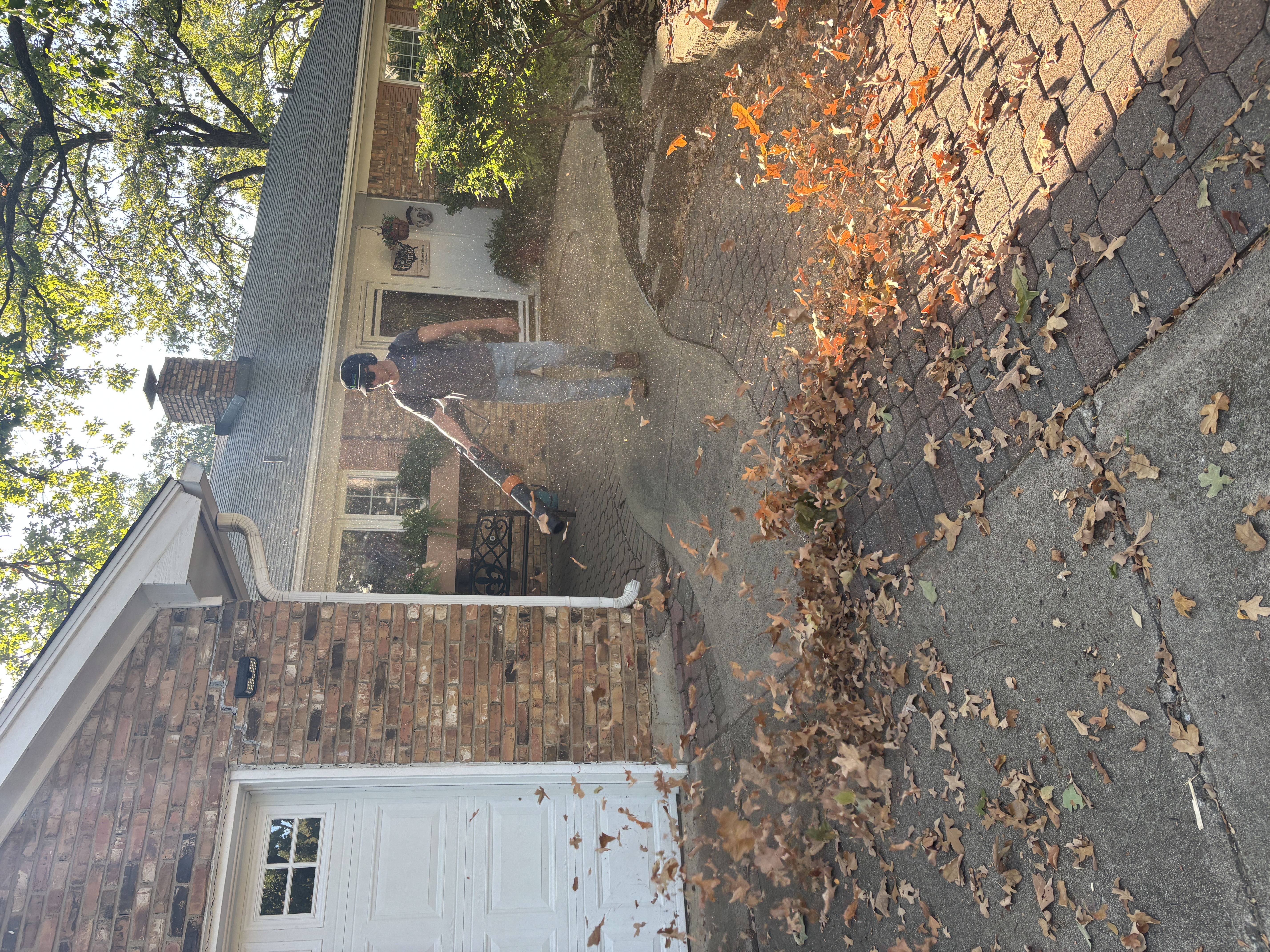 Visionary Outdoor Solutions team member blowing leaves off a residential driveway