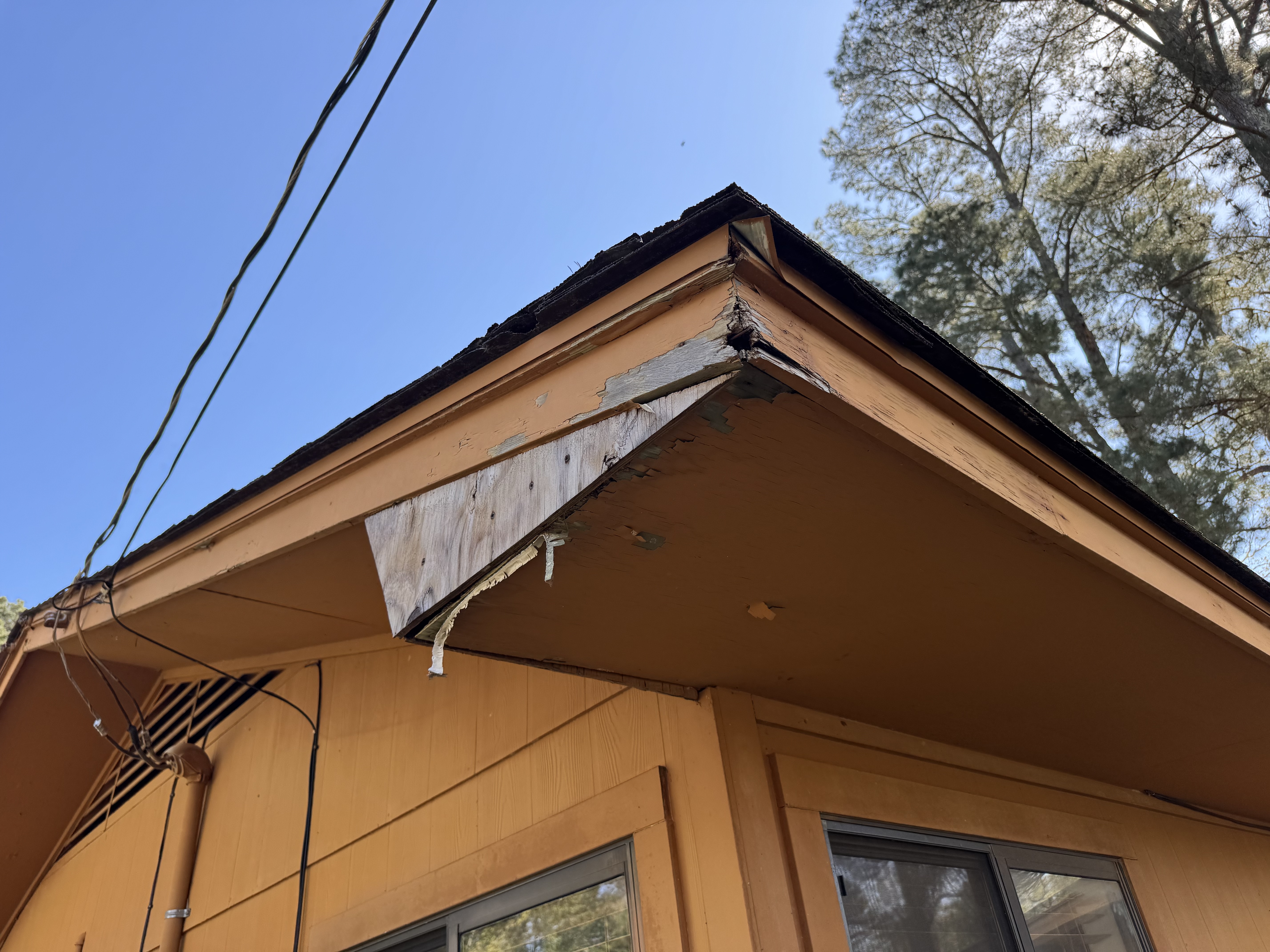 Exposed splintered wood at roof corner trim