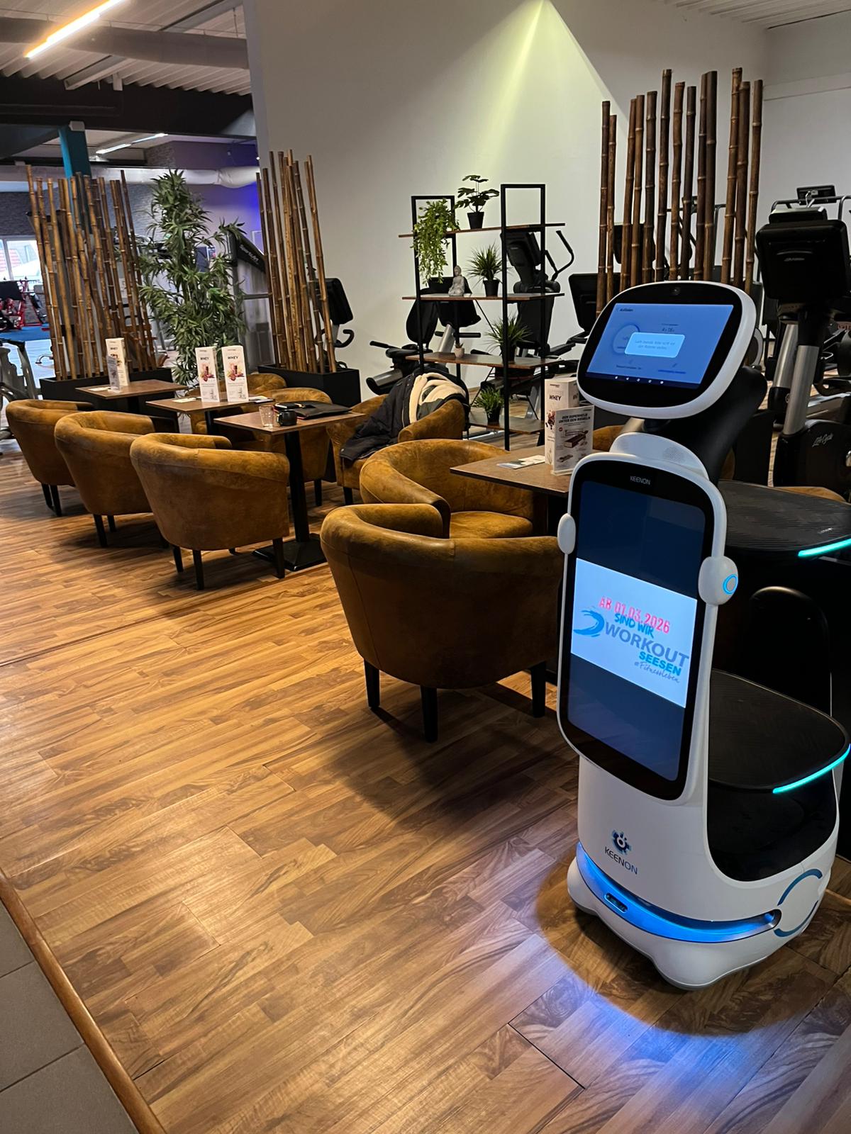 Serviceroboter mit Display und Ablagen vor Sitzplätzen und Fitnessgeräten im Workout Seesen