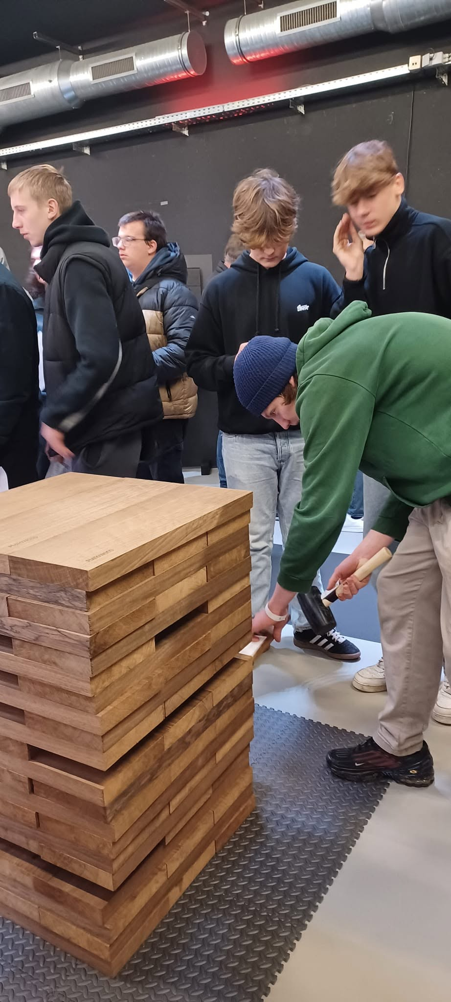 Leerling assembleert houten blokken met een houten hamer op de Inspiration Day