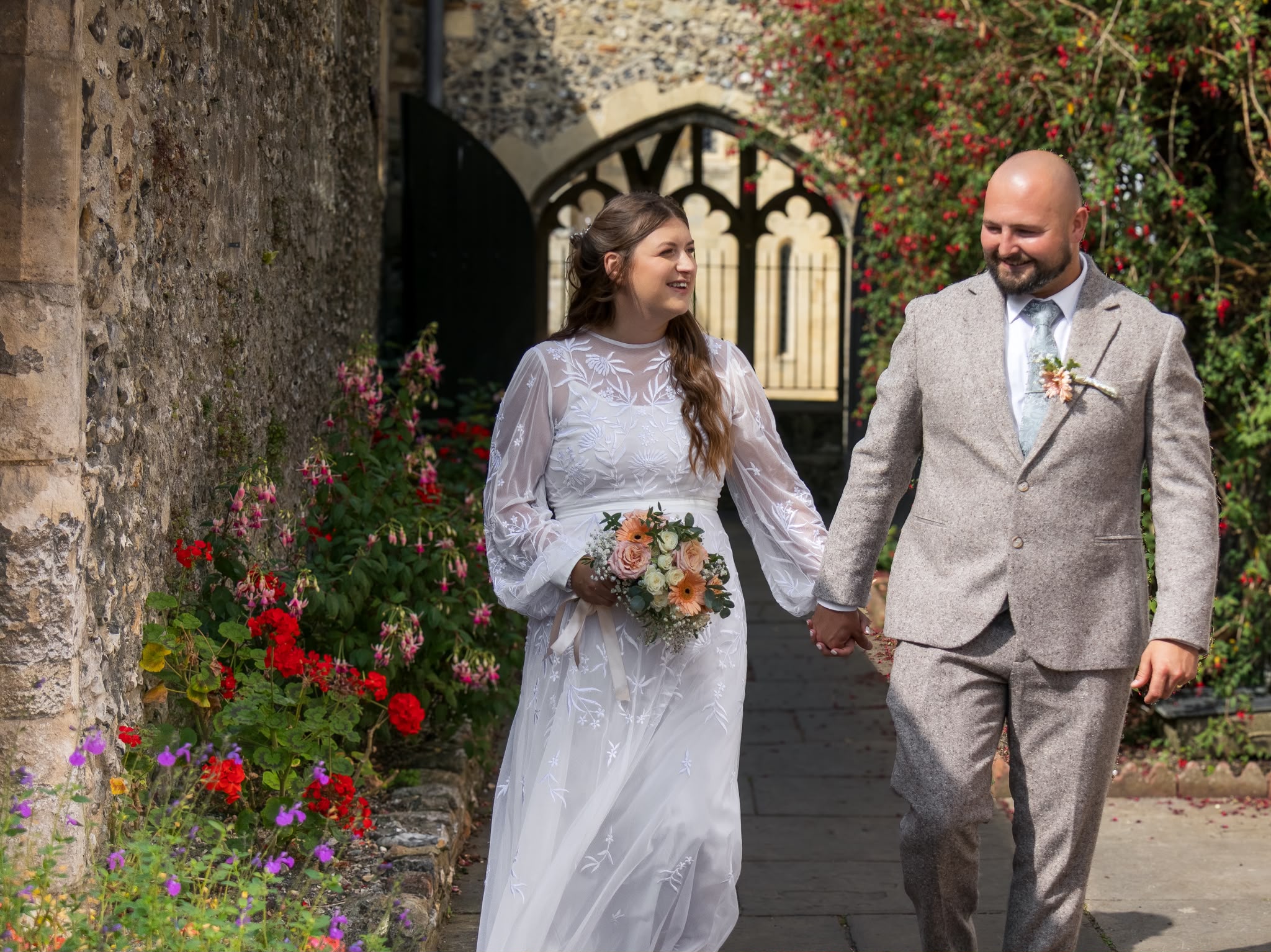 Bride and groom walking hand in hand along a stone pathway after their ceremony