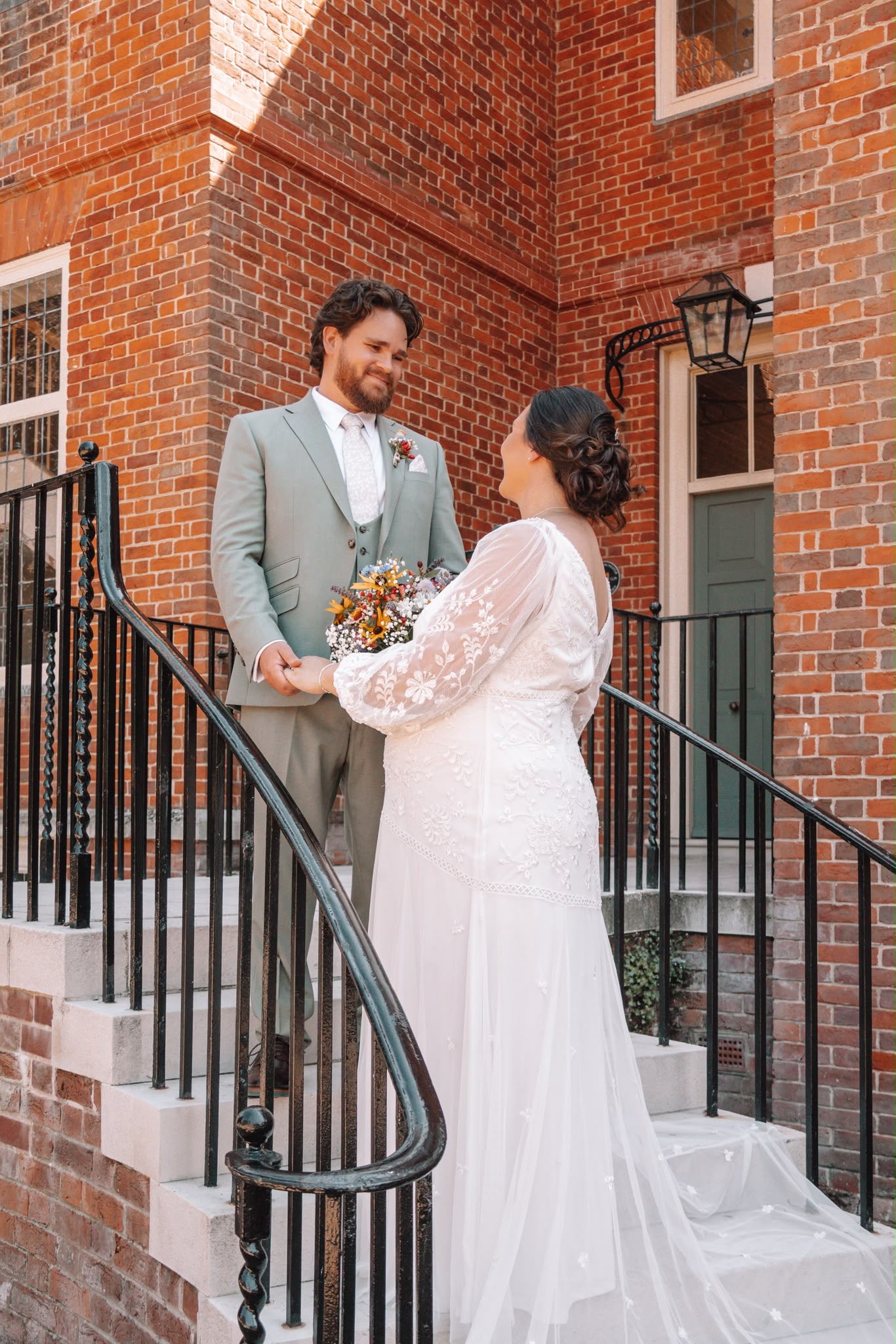 Bride and groom photographed together on the stone steps of a red brick wedding venue