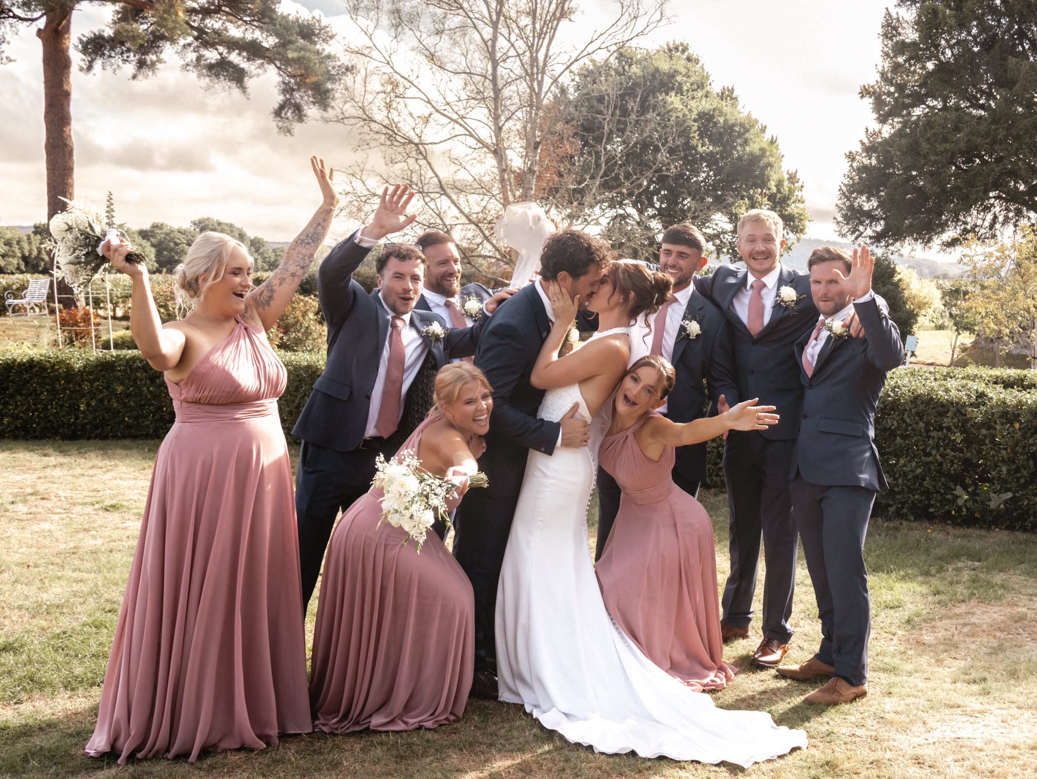 Bride and groom kissing surrounded by their wedding party in Chichester