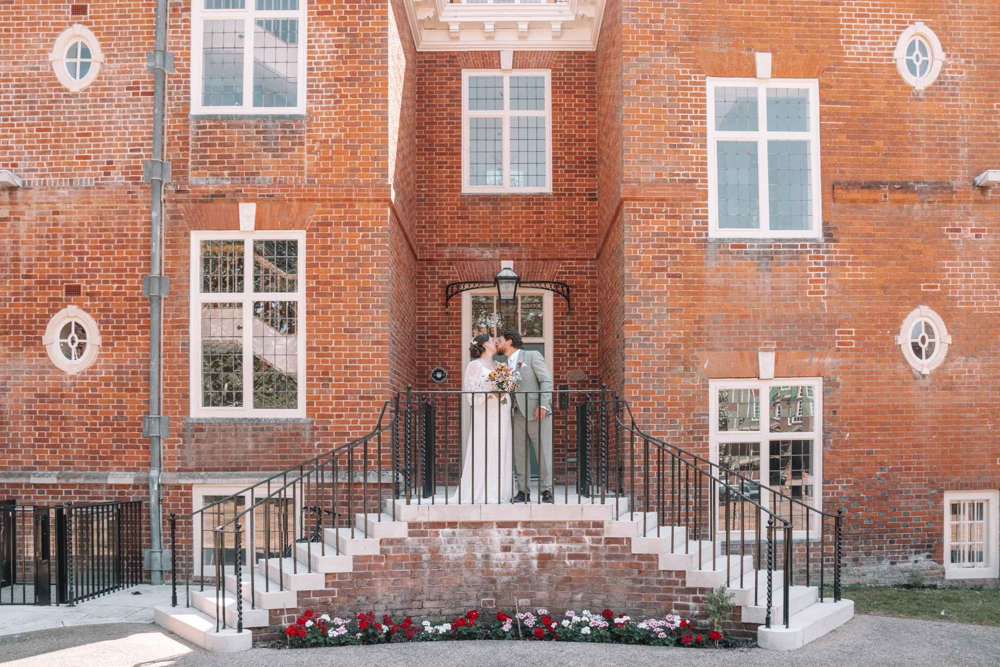 Bride and groom kissing on a brick landing in front of a historic red brick building