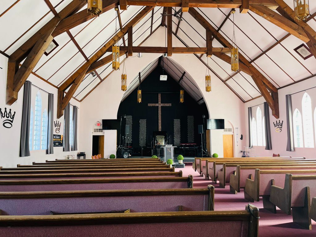 A diverse congregation lifting hands in a dimly lit, gold-hued worship hall